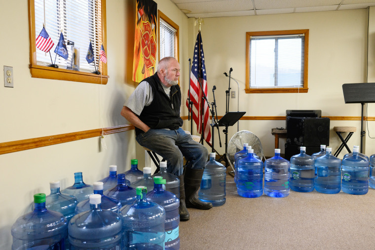 A town meeting attendee sits among water jugs donated to residents by the Center for Coalfield Justice in New Freeport, Pa., in March.