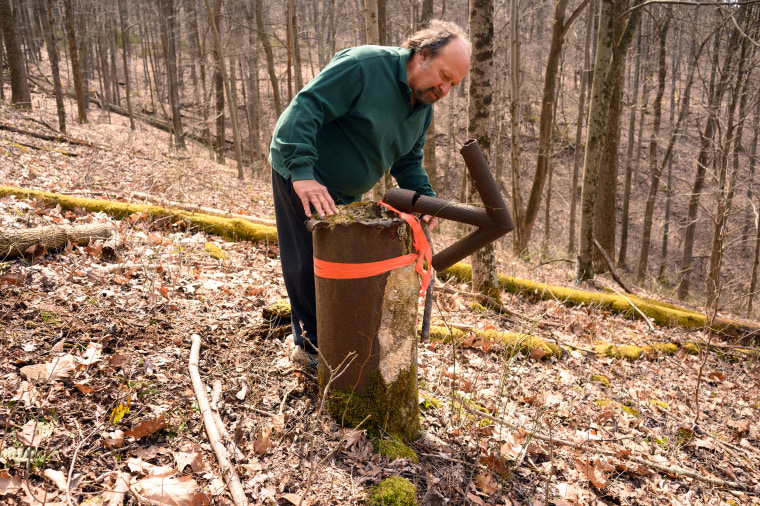 Tom Busoletti, a local stonemason, with an abandoned well in the woods near his home in New Freeport, Pa., on March 29, 2023.