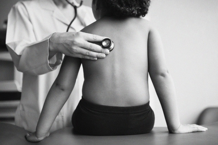 A pediatrician listens to a girl's lungs with a stethoscope.