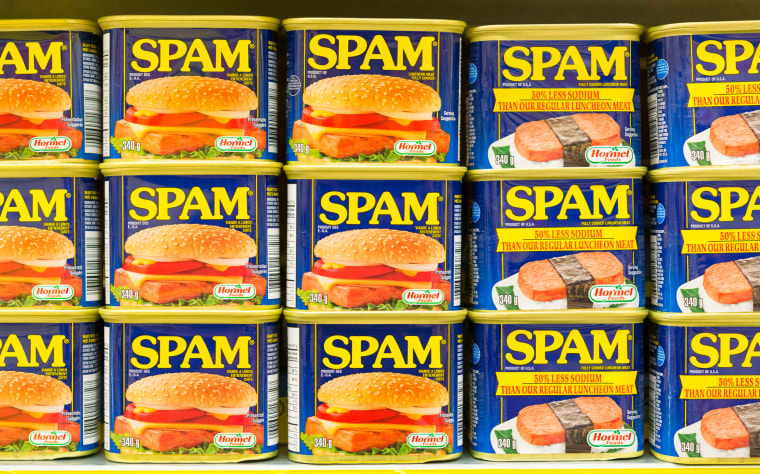 Spam canned meat stacked vertically in store shelf.