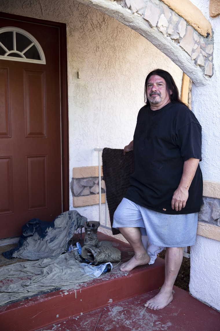 Brett Anthony Vasquez stands next to his muddy clothes outside of his home in Cathedral City, CA., on Tuesday, August 22, 2023.
