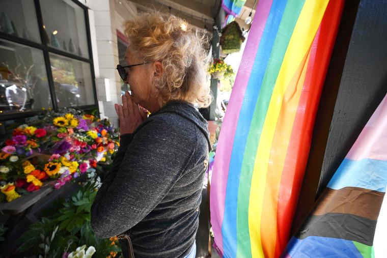 A resident reacts after leaving flowers at a makeshift memorial outside the Mag.Pi clothing store in Cedar Glen, near Lake Arrowhead, California, on August 21, 2023. The owner of the store, Laura Ann Carleton, was fatally shot on August 18 by a man who "made several disparaging remarks about a rainbow flag" displayed outside her store, according to the San Bernardino County Sheriff's department. The suspect was later killed during an encounter with deputies.