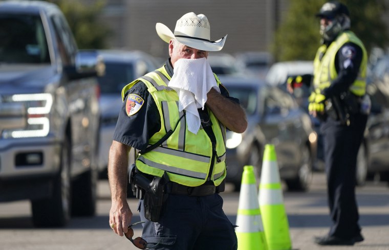 Police officer James Rhodes uses a wet towel to cool off as he directs traffic after a sporting event in Arlington, Texas, Saturday, Aug. 19, 2023. 