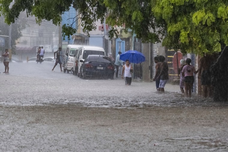 People walk through a street flooded by the rains of Tropical Storm Franklin in Santo Domingo, Dominican Republic