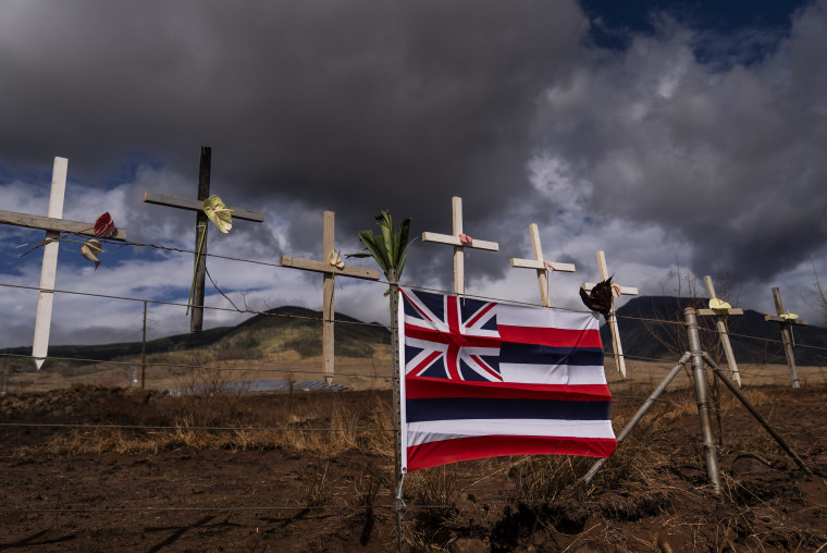 A Hawaiian flag and crosses honoring the victims killed in the wildfire in Lahaina adorn the Lahaina Bypass on Aug. 21, 2023.