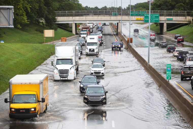 Lots of automobiles drive through a flooded area of I-94 in Detroit on Friday, on Aug. 25, 2023.