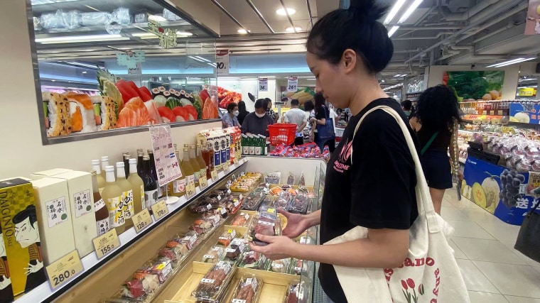 Dolly Peng, 23, looks at sushi in a Hong Kong store that has a sign saying it is from Norway, Argentina and Canada.