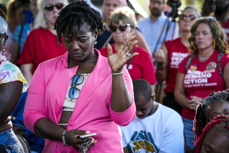 Image: A woman attending a vigil for the victims of Saturday's mass shooting bows her head in prayer on Aug. 27, 2023, in Jacksonville, Fla.