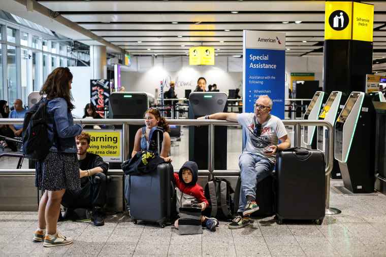 A family waits as their flight delays as Britain's National Air Traffic Service (NATS) restricts UK air traffic due to a technical issue causing delays, in London on Aug. 28, 2023.