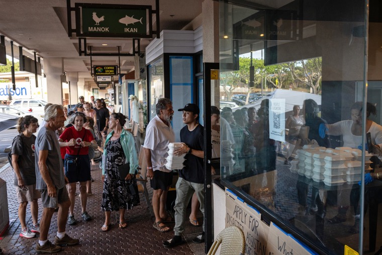 People stand in line to pick up free venison chili for dinner at Joey's Kitchen, a Hawaiian-Filipino fusion restaurant, in Napili on West Maui on Aug. 21, 2023. 