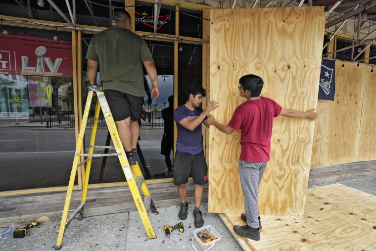 Workers at board up restaurant windows Tuesday, Aug. 29, 2023, in Clearwater, Fla.