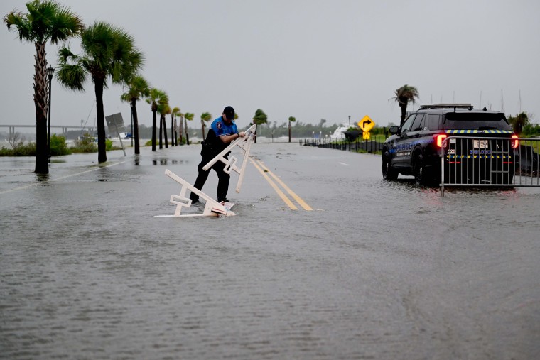 A Charleston City Police Officer picks up a road barricade in preparation to block off Lockwood Dr in Charleston, S.C., on Aug. 30, 2023