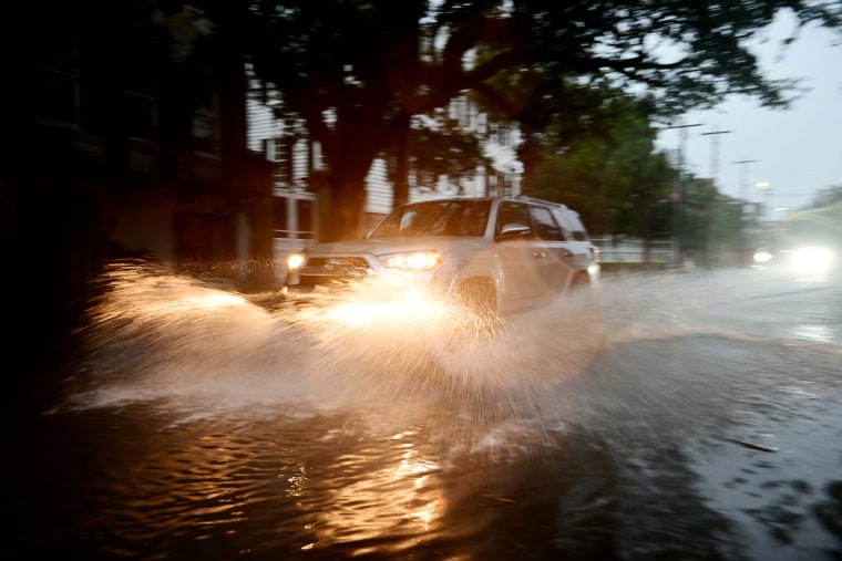 Cars drive through downtown Charleston, S.C., as waters rise on Aug. 30, 2023.