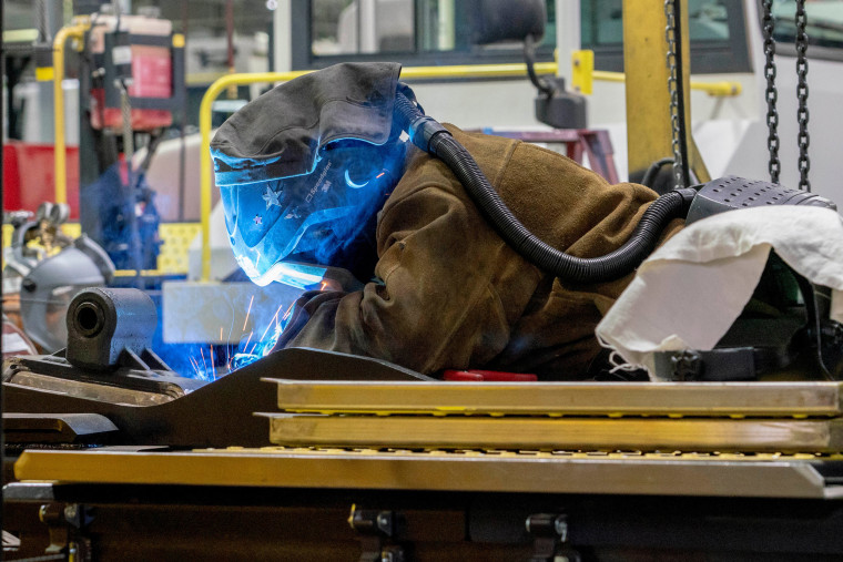 An employee welds inside a manufacturing facility.