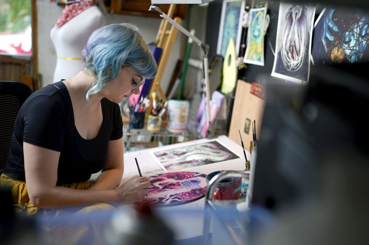 Artist Kelly McKernan paints in their studio in Nashville, Tenn.