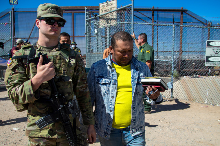 Migrants are escorted by a U.S. Army soldier after entering into El Paso, Texas from Ciudad Juarez, Mexico to be processed by immigration authorities, May 10, 2023. 