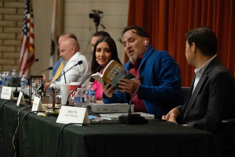 Unified School District Board clerk Andrew Cruz reads from "Gender Queer" after the board voted on July 20, 2023 to pass a policy that would force teachers to out their trans and gay students to their parents. Board president Sonja Shaw looks on.