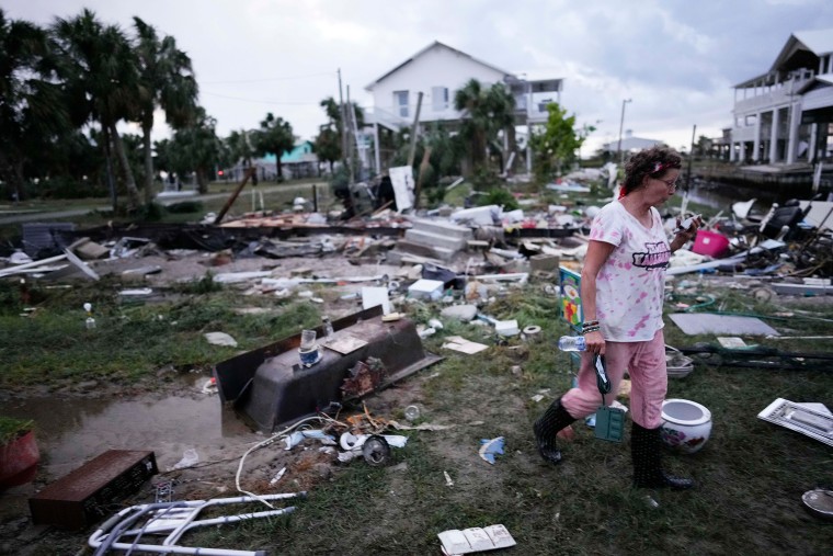 A woman walks amidst debris strewn across the yard where her mother's home had stood, as she searches for anything salvageable in Horseshoe Beach, Fla., after the passage of Hurricane Idalia, on Aug. 30, 2023. 