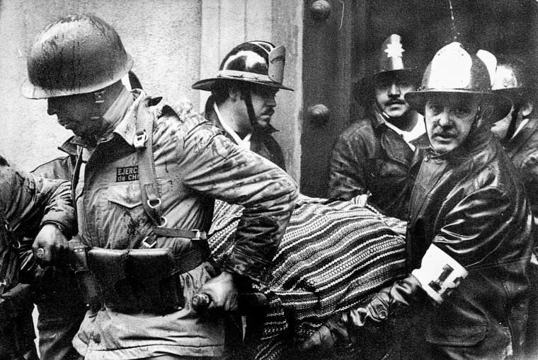 Soldiers and firefighters carry the body of President Salvador Allende, wrapped in a Bolivian poncho, out of the destroyed La Moneda presidential palace after the coup led by Gen. Augusto Pinochet that ended Allende's three-year government, in Santiago, Chile, on Sept. 11, 1973.