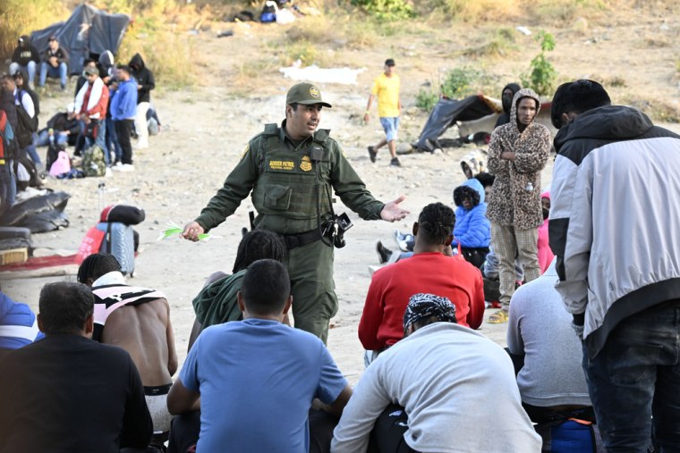 Un agente de la Patrulla Fronteriza de Estados Unidos habla con migrantes en la frontera con México el 8 de mayo de 2023.