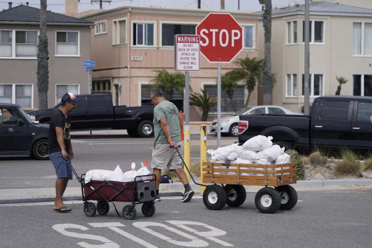Residentes de Long Beach, en California, trasladan bolsas con arena, el sábado 19 de agosto de 2023.
