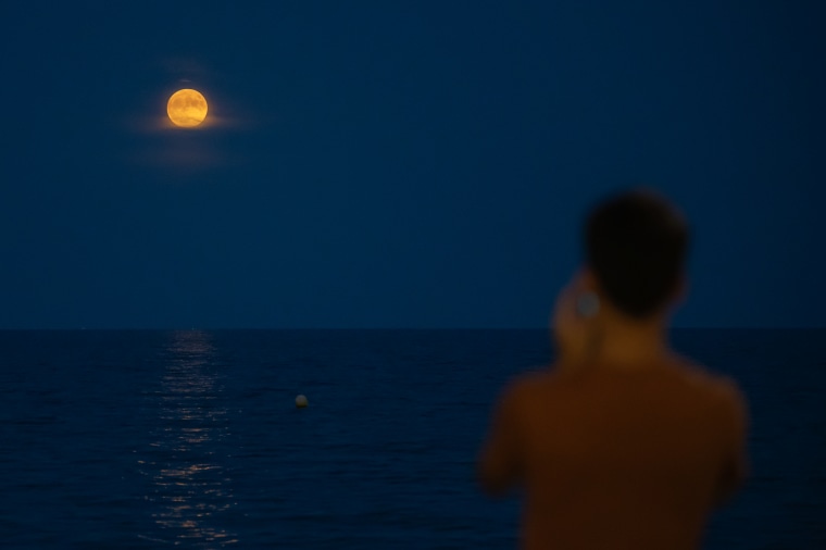 La superluna "Luna Azul" atraviesa franjas de nubes bajas mientras se eleva sobre el mar Mediterráneo en Alicante, el 30 de agosto de 2023.