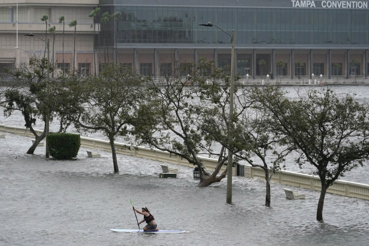 Zeke Pierce monta su tabla de surf en medio del Bayshore Blvd inundado en el centro de Tampa, Florida.
