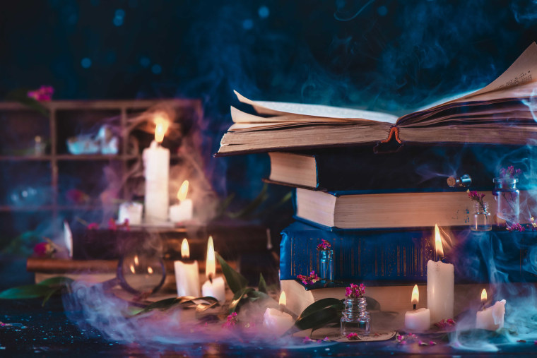 Stack of vintage books in fantasy scene with candles. Magical studies and reading in candlelight concept. Dark still life with copy space.