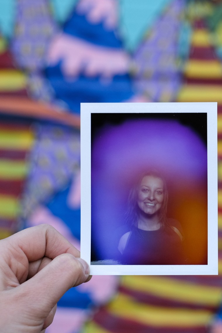 A woman holding an aura Polaroid portrait of herself.