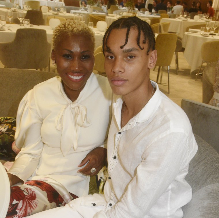 Nicole Coste and her son Alexandre in casual white outfits in a ballroom.