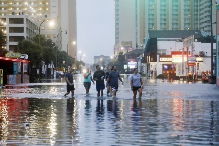People walk up a flooded Ocean Boulevard in North Myrtle Beach, S.C. on Aug. 30, 2023 after the passage of Hurricane Idalia. 