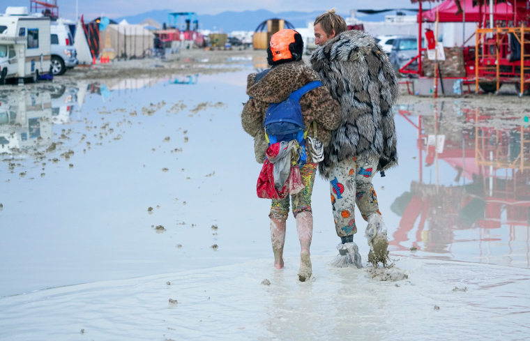 People walk through the mud at Burning Man