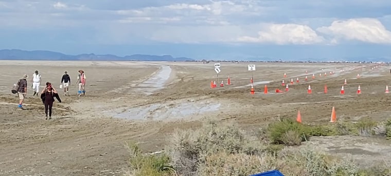 A few festival-goers hike out of Burning Man's mud flats en route to an accessible road on Saturday, Sept. 2, 2023, in Black Rock City, Nev.