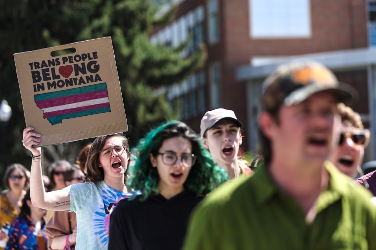 Transgender rights activists hold signs as they march through the University of Montana campus on May 3, 2023 in Missoula, Mont.