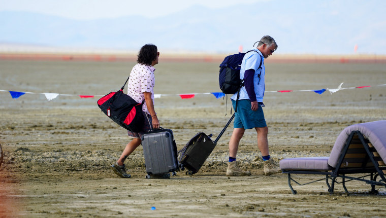 People walk towards the city limits of Burning Man in Black Rock Desert, Nev., on Sept. 3, 2023.