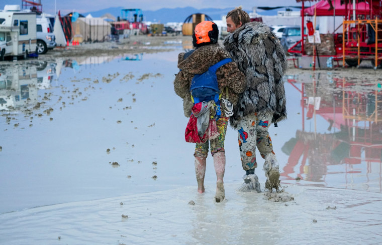 Burning Man attendees trudge through the mud in Black Rock City, Nev., on Sept. 2, 2023.