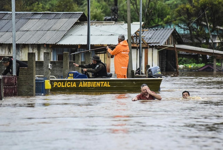 Image: Police officers check a house as residents wade through a flooded street after floods caused by a cyclone in Passo Fundo, Rio Grande do Sul state, Brazil, on Sept. 4, 2023.