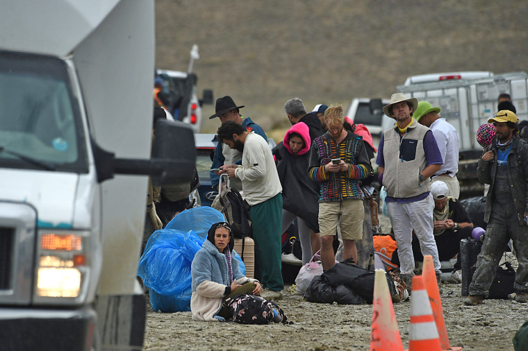 People wait for a shuttle bus to take them to Gerlach and Reno on the side of Highway 34 out near the Burning Man site on the