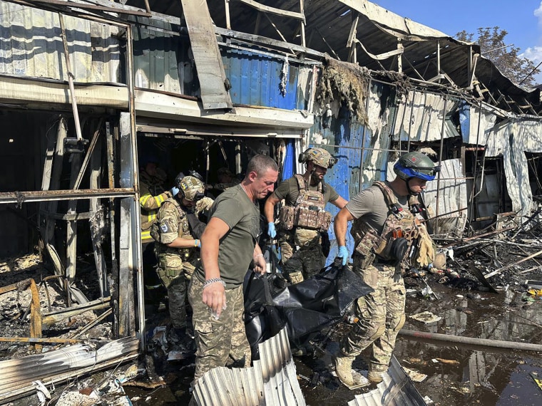 Soldiers and rescue workers carry a body a victim after the Russian rocket attack on a city market in Kostiantynivka, Ukraine