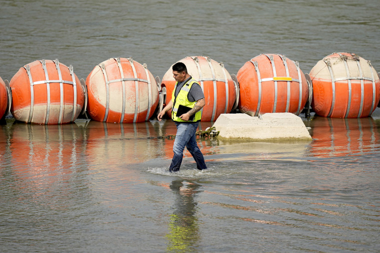 A worker inspects buoys being used as a barrier along the Rio Grande, Monday, Aug. 21, 2023, in Eagle Pass, Texas.