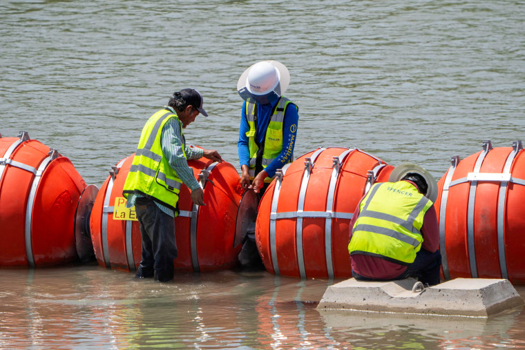 Workers provide maintenance to the blades between the buoys placed along the Rio Grande border with Mexico to prevent migrants from entering the U.S. in Eagle Pass, Texas, on Aug. 25, 2023.