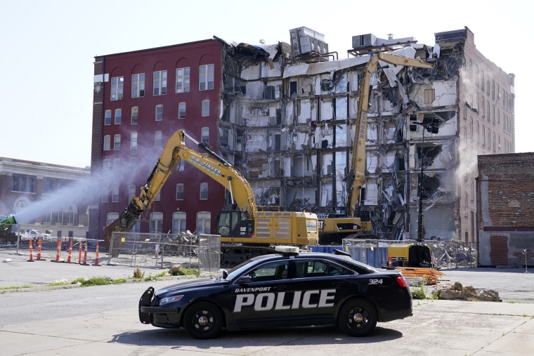 A police officer sits parked at the site of a building collapse in Davenport, Iowa