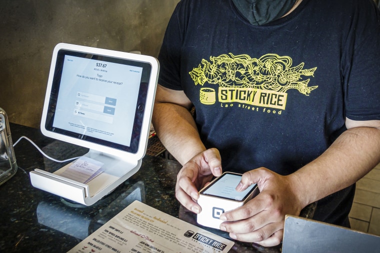 An employee processes a Square credit card reader at a restaurant in Orlando, Fla., in 2020.
