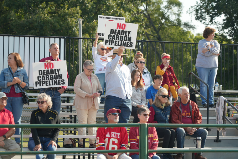 Crowd members hold up signs against the use of eminent domain to install CO2 pipelines on private land at a political rally Saturday, Sept. 9, 2023, in Nevada, Iowa.