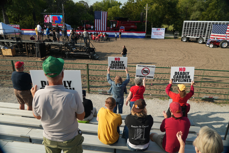 Crowd members hold up signs against the use of eminent domain to install CO2 pipelines on private land while Iowa Gov. Kim Reynolds speaks at a political rally Saturday, Sept. 9, 2023, in Nevada, Iowa.