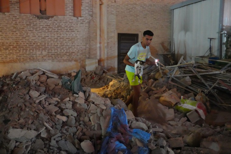 A man carries a cat through the rubble of a partially collapsed mosque on Sept. 9, 2023 in Marrakech, Morocco. 