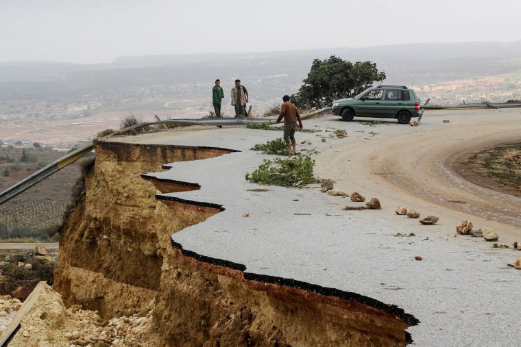 People stand on a damaged road after a powerful storm and flooding hit Shahhat, Libya, on Sept. 11, 2023.