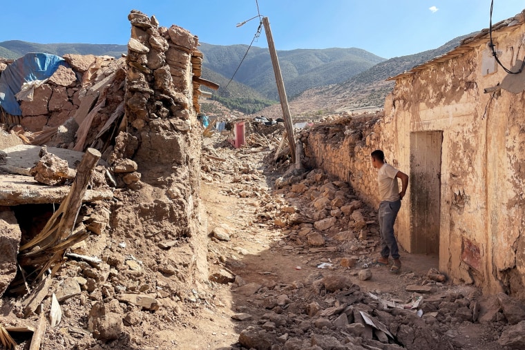 A person stands near damaged houses in Tafeghaghte
