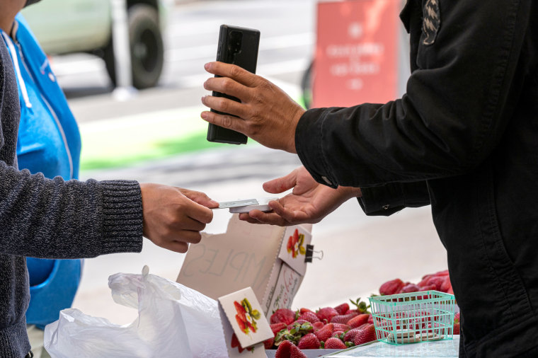 A shopper pays for produce with a credit card at a farmers market in San Francisco, California, US, on Thursday, June 2, 2022. The Biden administration announced $2.1 billion in new funding Wednesday to bolster food supply chains, including efforts to support smaller processors and help farmers shift to organic production. Photographer: David Paul Morris/Bloomberg via Getty Images