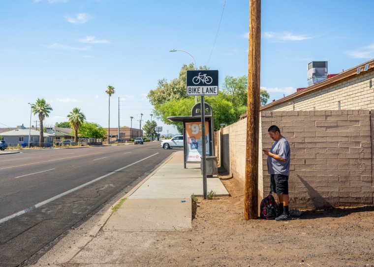 Image: Adrian Mata stands in the shade while waiting for the bus in Phoenix on July 15.